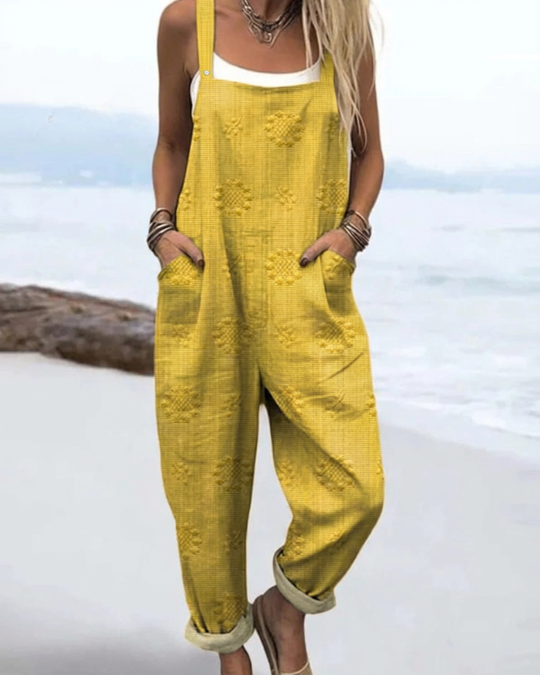 Woman posing in a flowy floral jumpsuit with wide-leg styling on a plain backdrop.