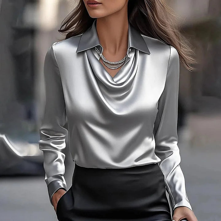 Elegant women’s blouse with a soft shimmer displayed on a plain background.