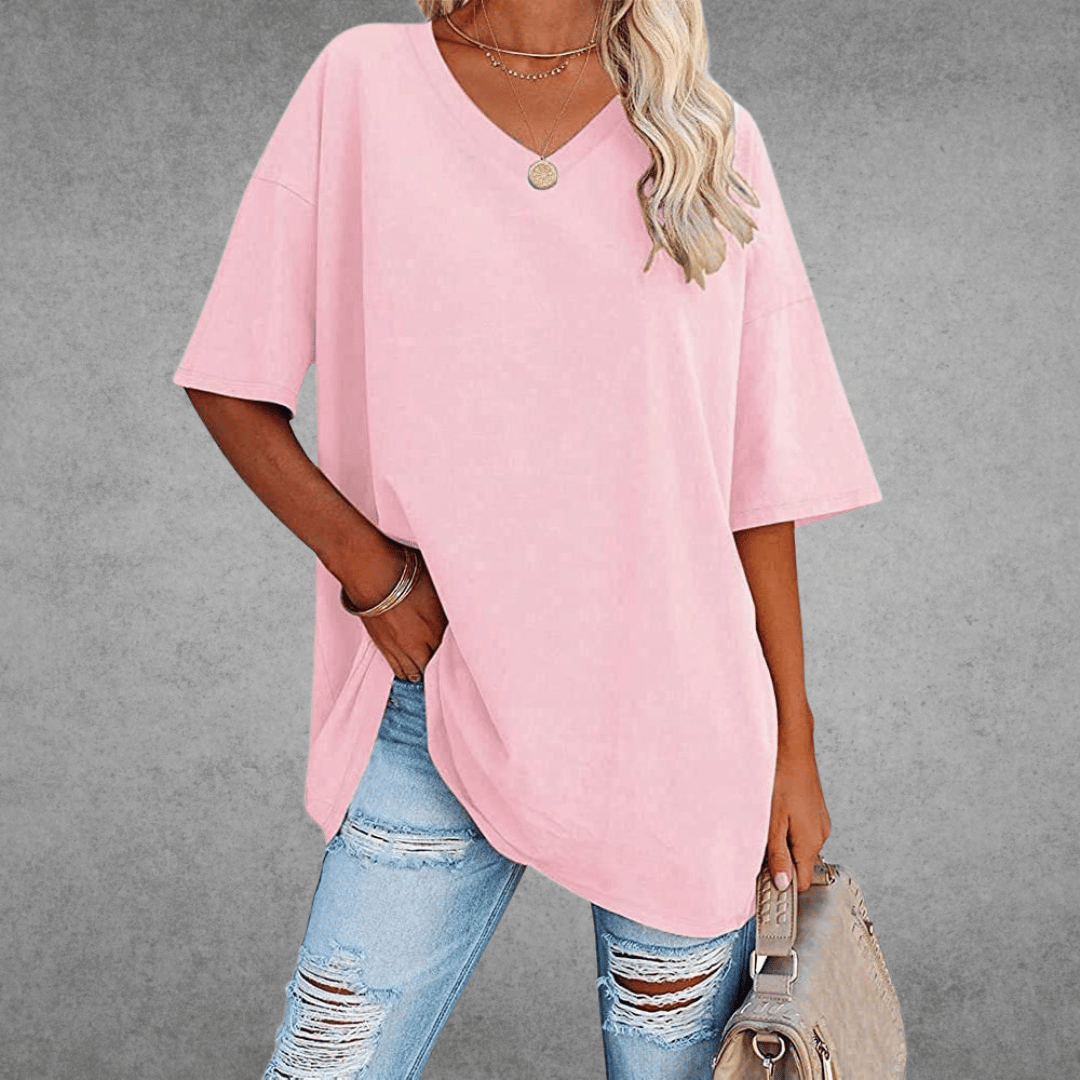 Woman modeling loose casual shirt, carrying bag, gray plain background.