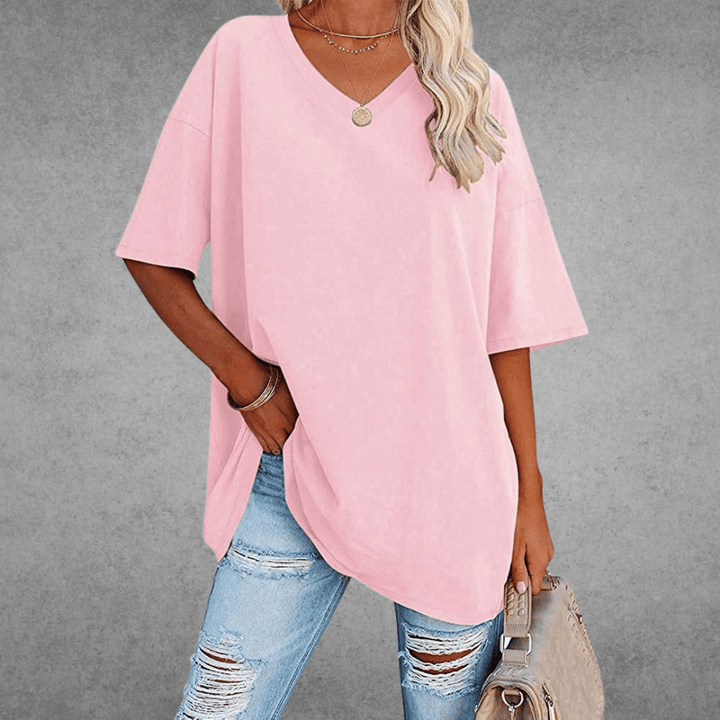Woman modeling loose casual shirt, carrying bag, gray plain background.