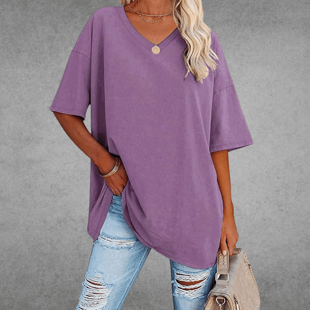 Stylish oversized V-neck outfit with bag, woman on gray background.