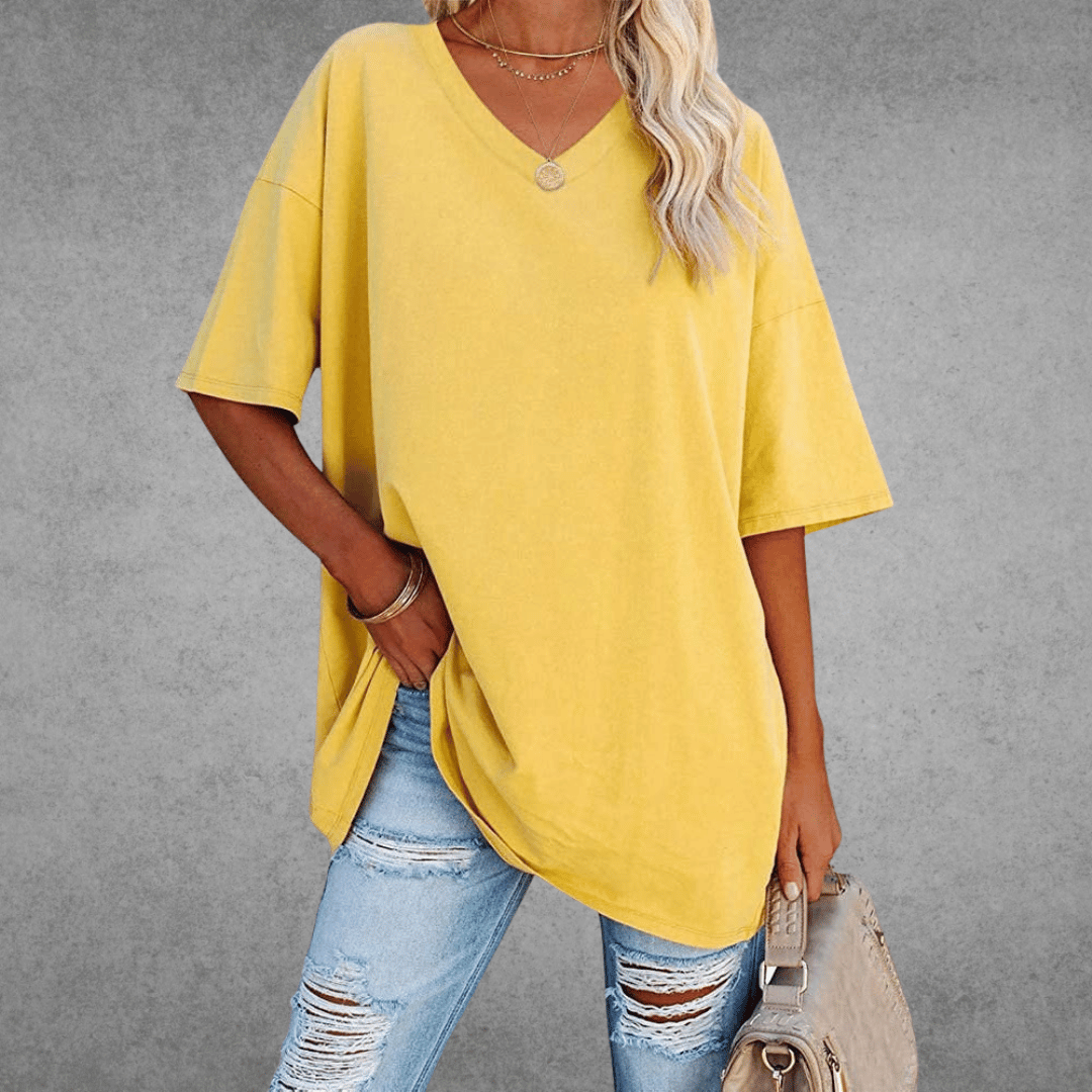 Loose-fitting V-neck shirt modeled by woman, gray plain background.
