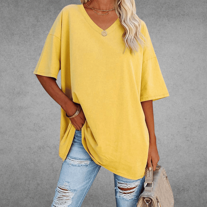 Loose-fitting V-neck shirt modeled by woman, gray plain background.