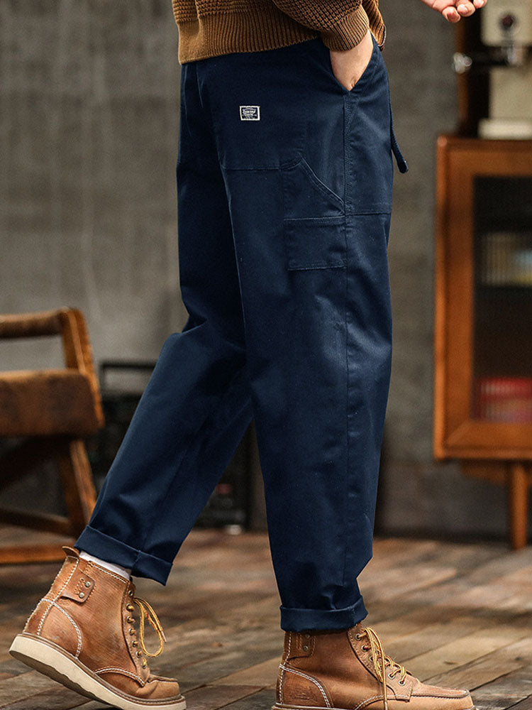 Male model displaying relaxed-fit cargo trousers with practical storage pockets on a plain background.