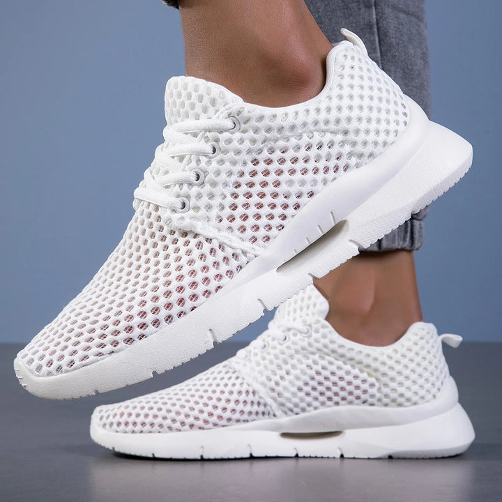 Female model showing lightweight mesh sneakers on a plain background.