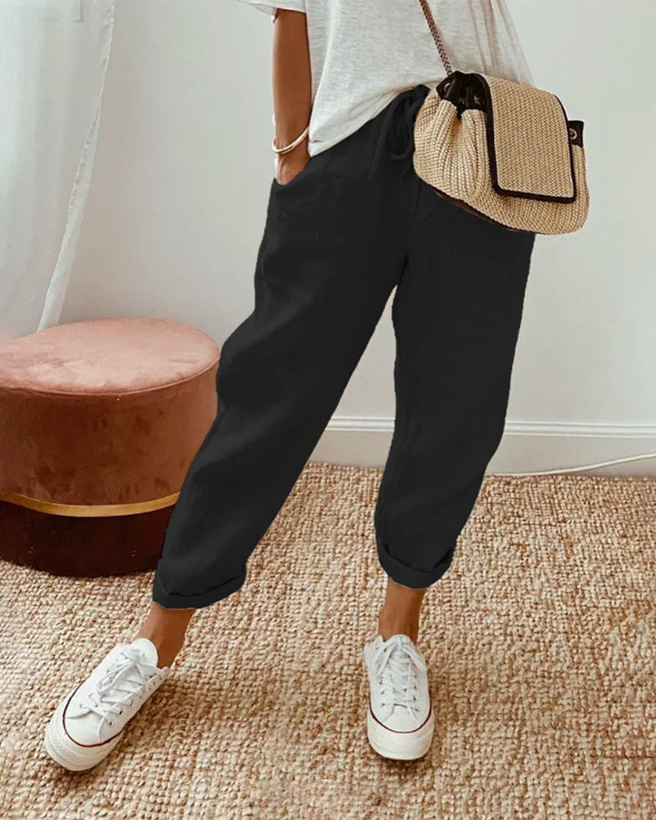 Female model styling casual tailored trousers on a clean background.