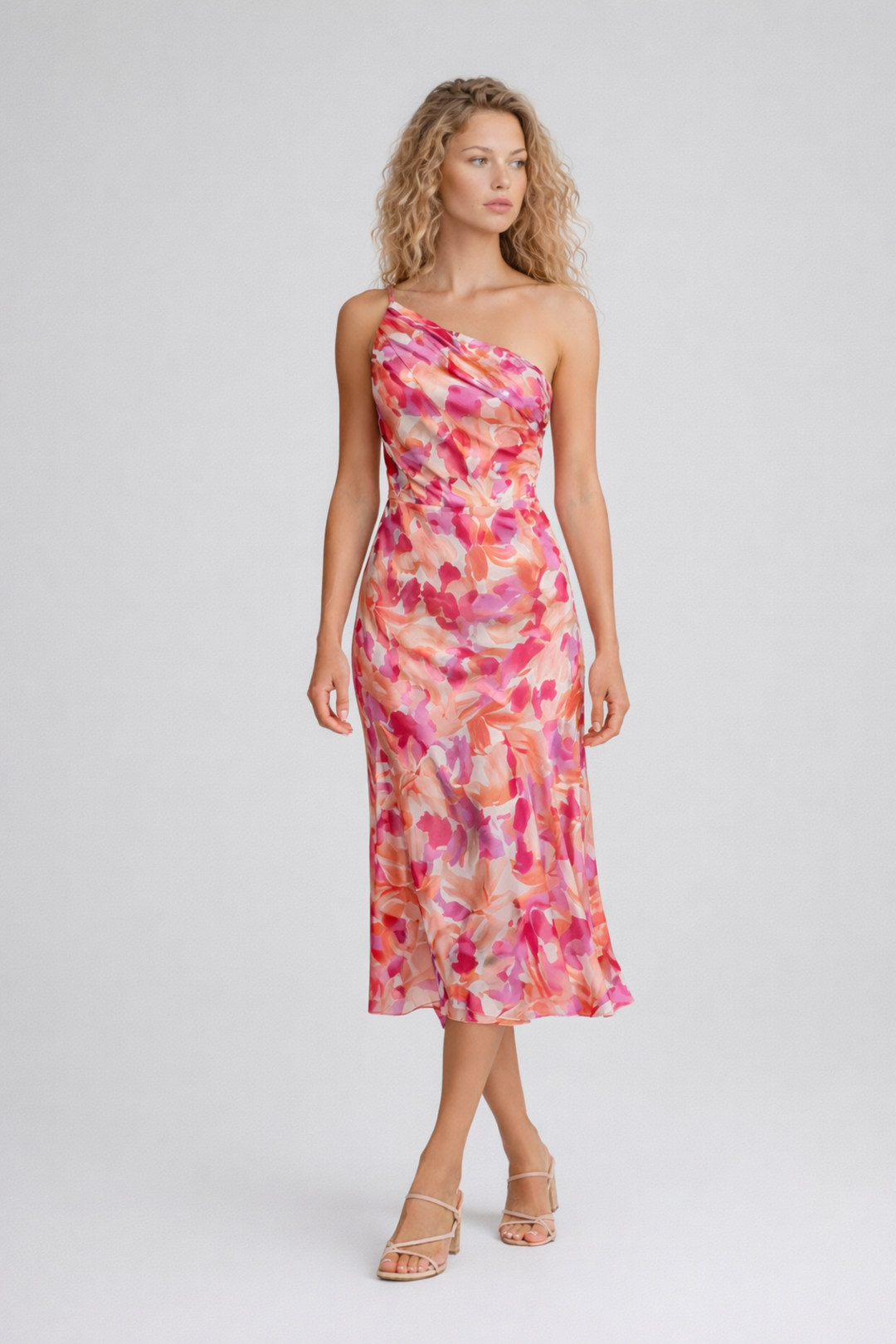 Woman wearing a sleeveless floral midi dress with a flowing skirt on a plain background.