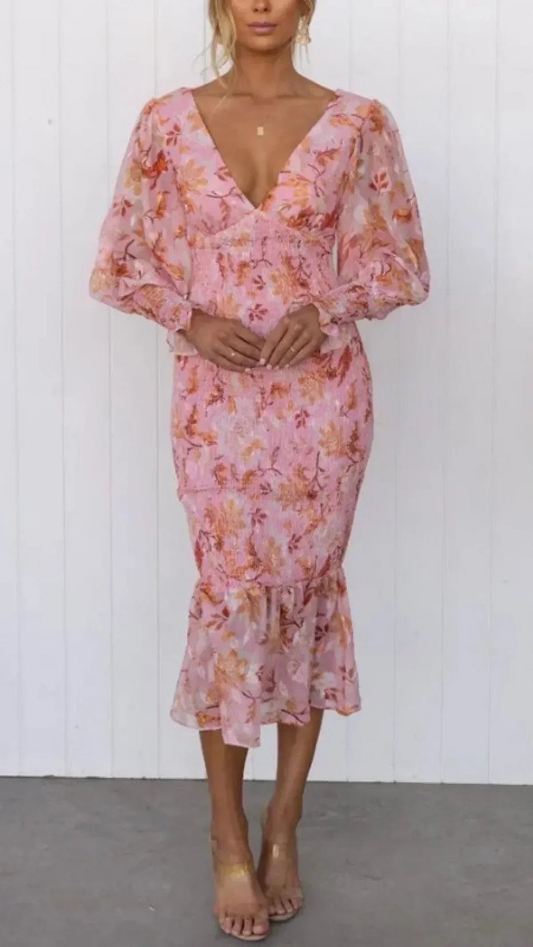 Woman wearing a vibrant floral dress against a plain background.