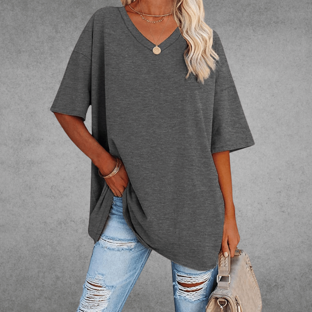 Chic oversized V-neck look with bag, gray plain background.