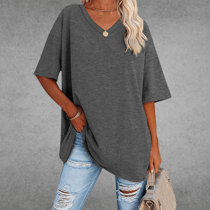 Chic oversized V-neck look with bag, gray plain background.