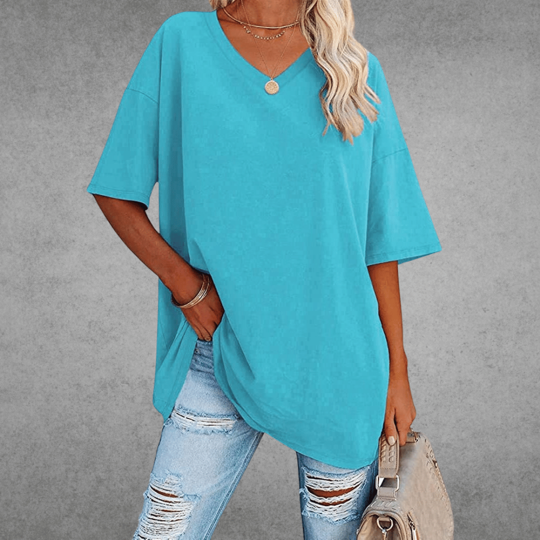 Casual oversized shirt front angle, woman holding bag, gray background.