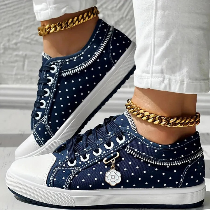 Woman modeling casual lace-up walking sneakers on a plain backdrop.