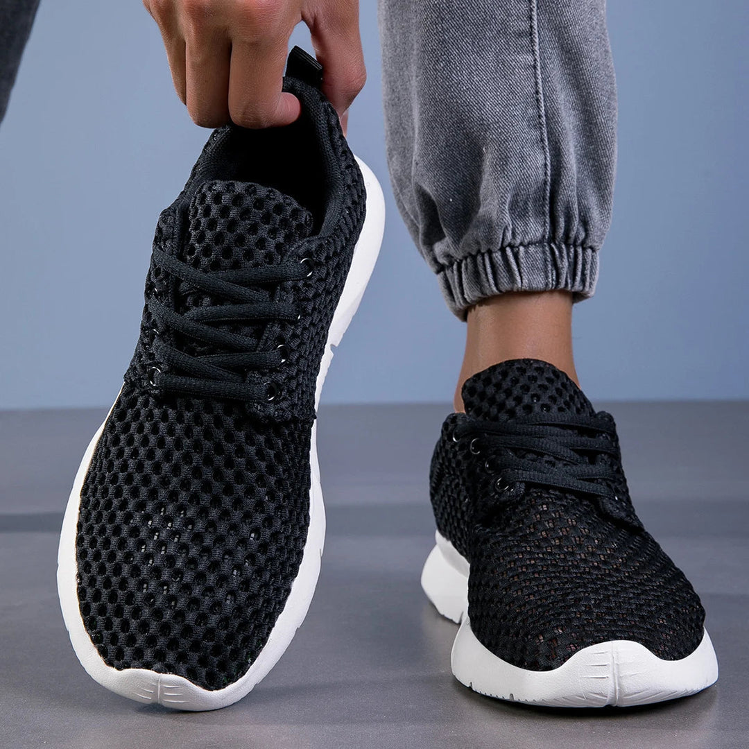 Breathable lace-up sneakers shown on female feet with a plain background.