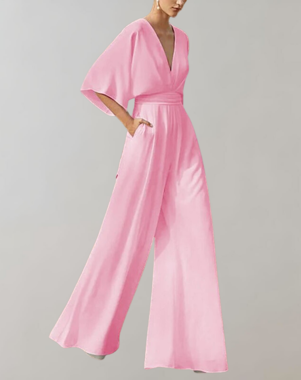 Woman posing in a flowing deep V-neck jumpsuit with wide sleeves on a plain background.