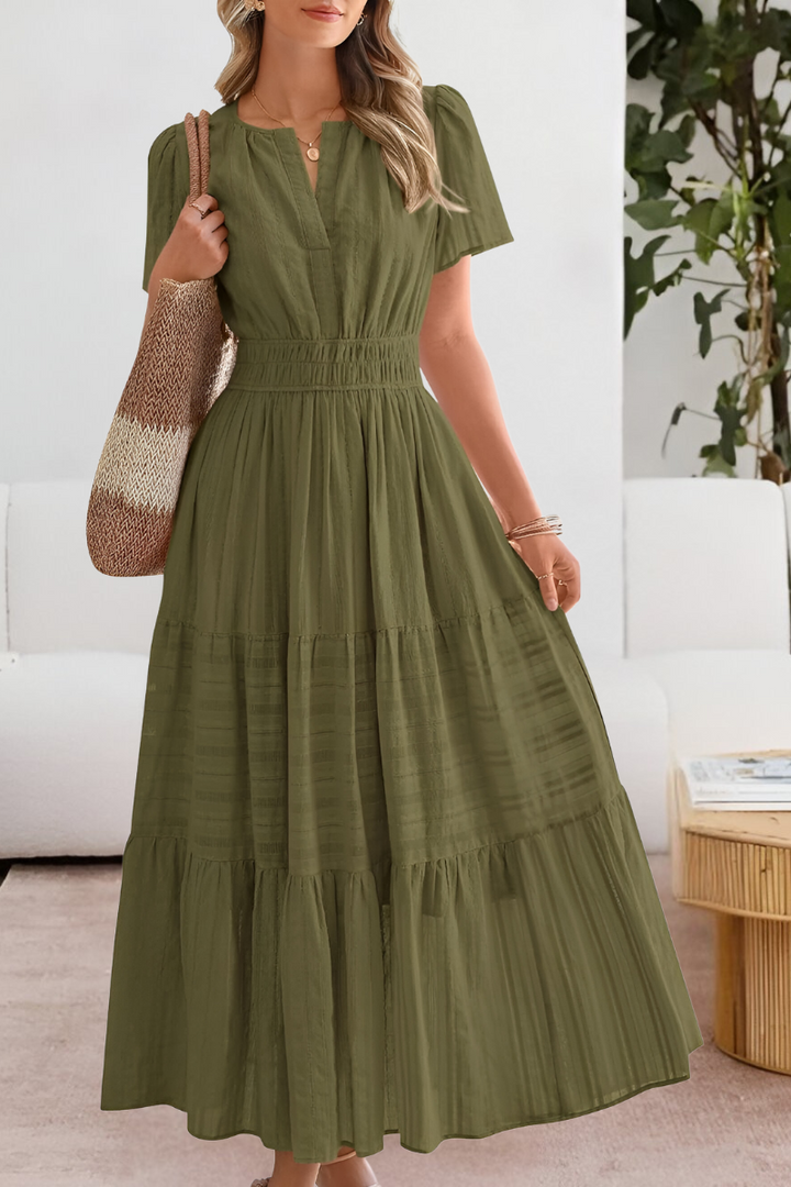 Female model in a casual boho dress with flowing movement on a plain background.