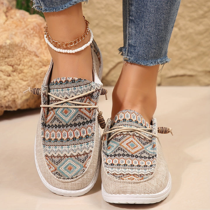 Close-up of patterned sneakers worn on feet against a simple background.