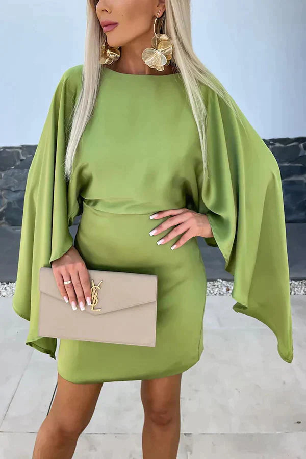 Female model wearing a black cape-sleeve mini dress against a plain background.