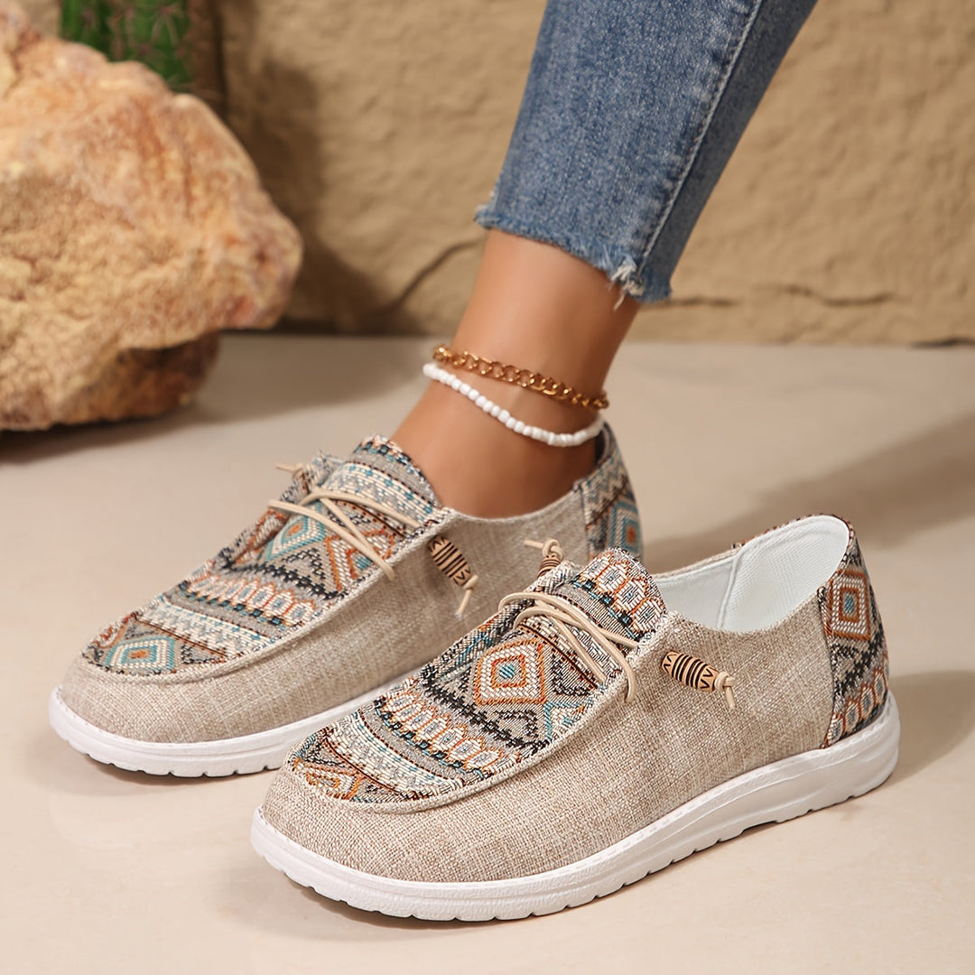 Women’s feet wearing bold patterned sneakers with a plain backdrop.