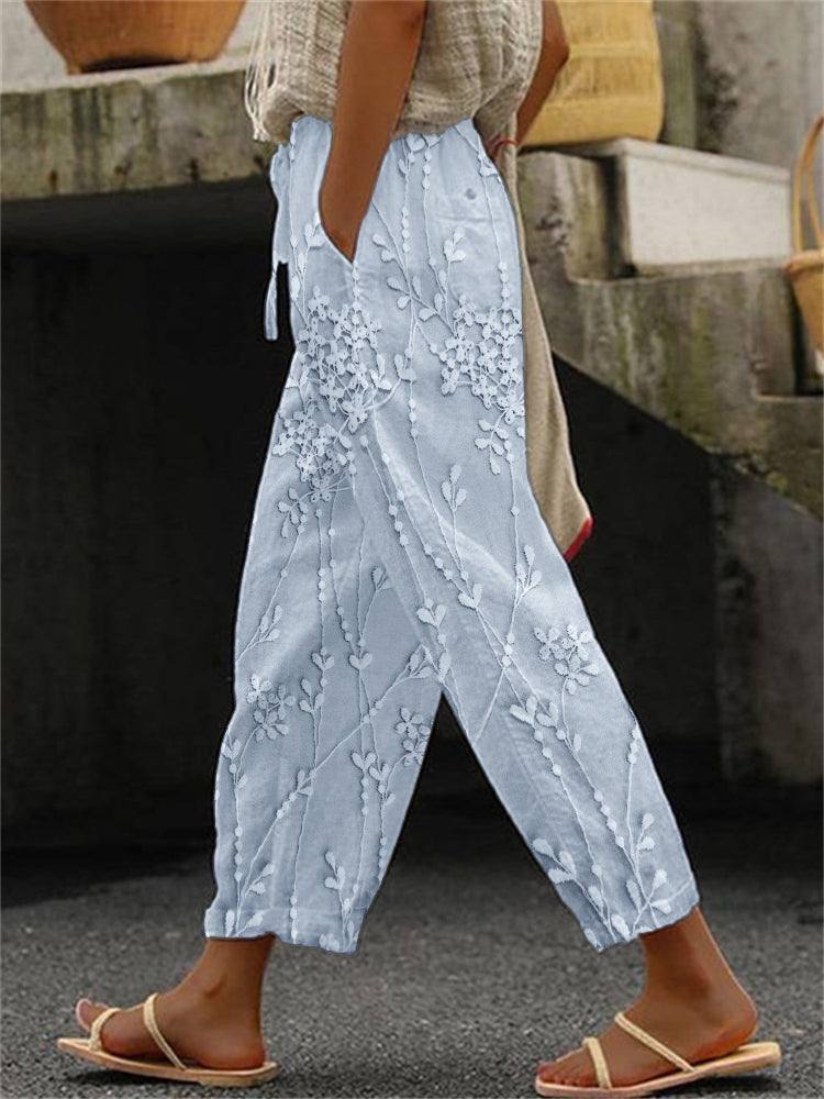 Woman showcasing printed trousers with a relaxed fit on a plain background.