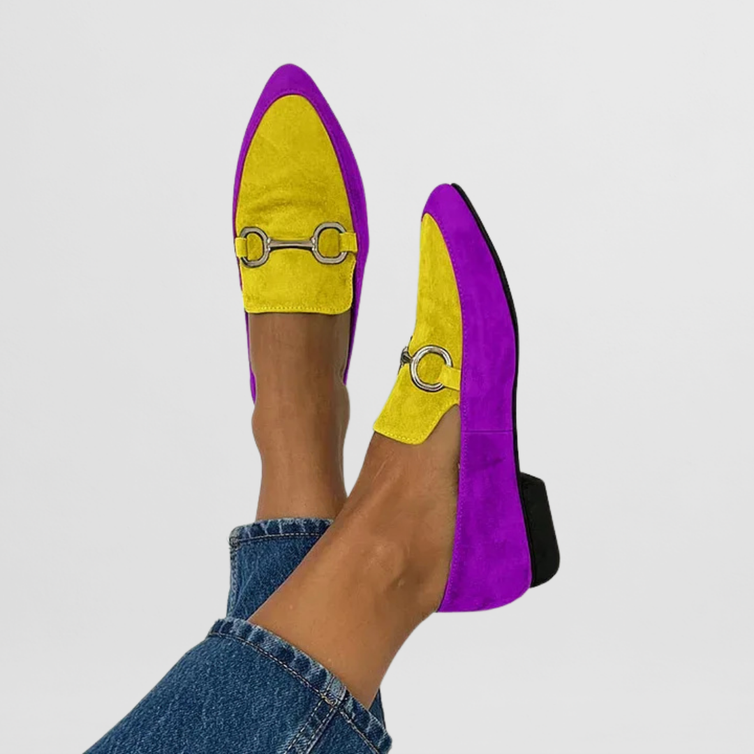 Woman wearing colorful casual moccasins with a simple plain backdrop.