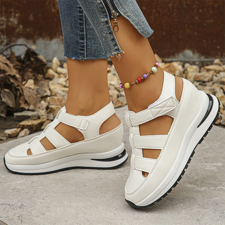 Feet shown in white platform-style sneakers with strap accents.