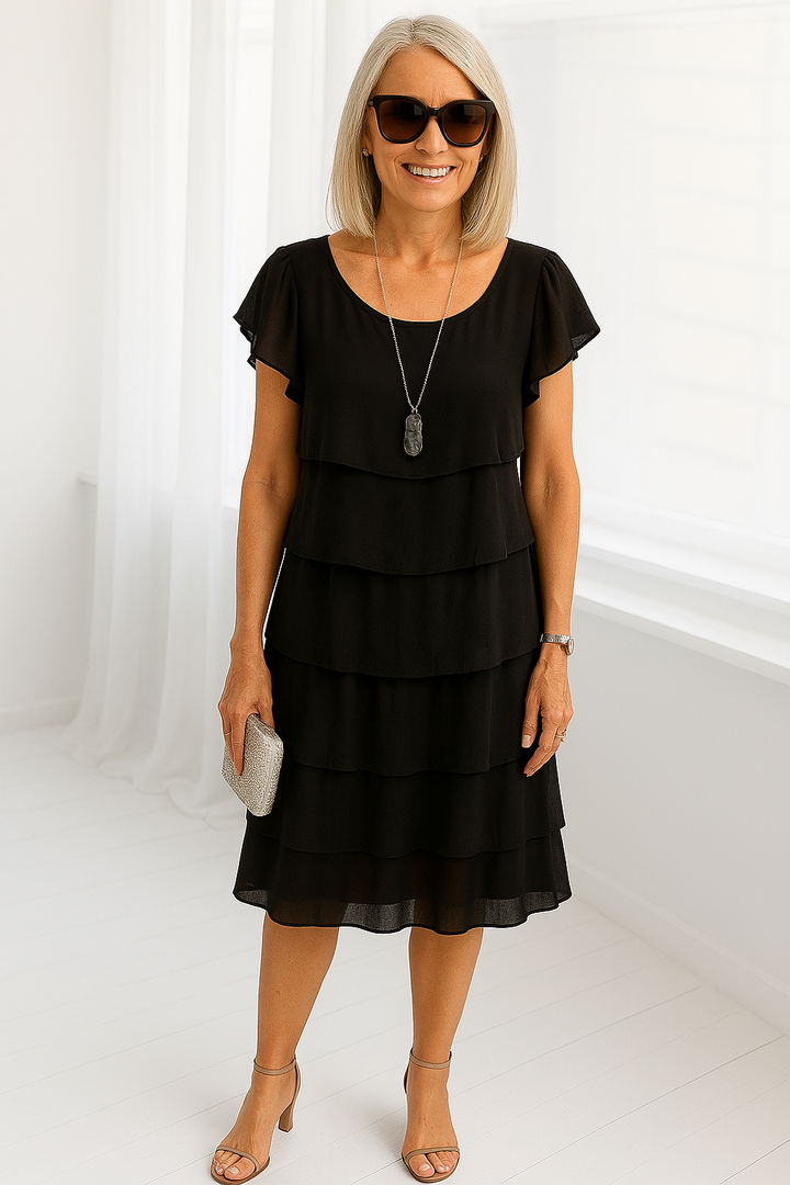 Female model in a flowing layered midi dress against a plain background.