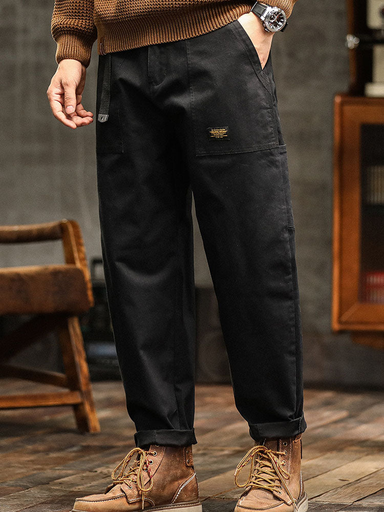 Male model wearing cargo pants with rolled hems and utility styling against a plain background.