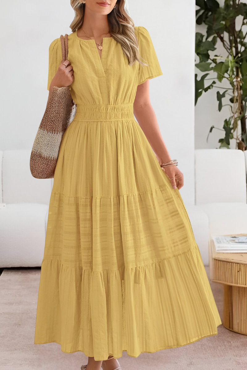 Female model wearing a flowing boho summer maxi dress on a plain background.