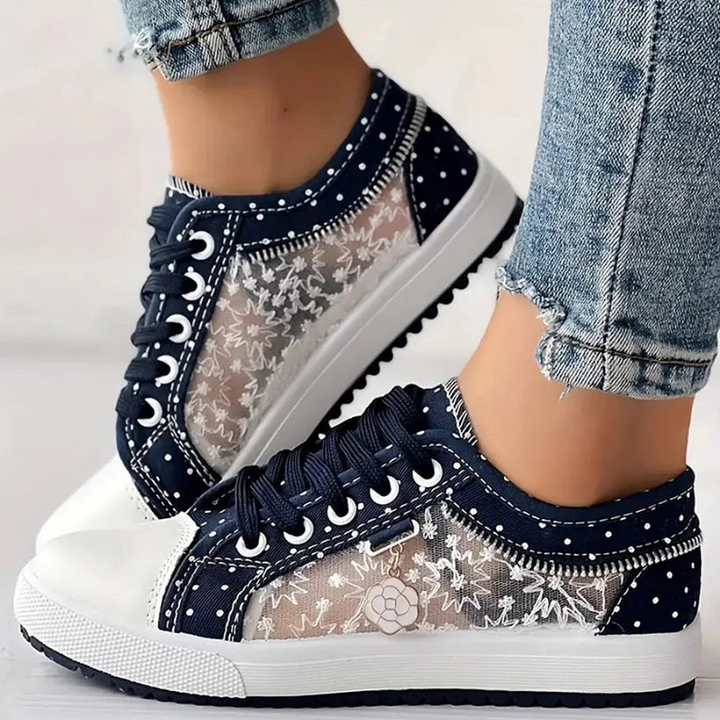 Female model standing in soft step sneakers with a plain background.