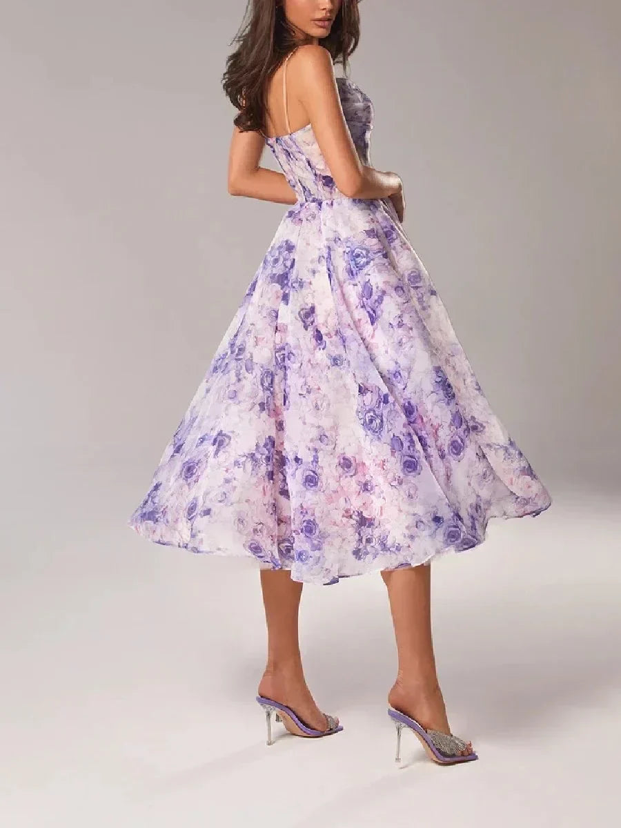 Woman showcasing a strapless floral midi dress with a defined waist and voluminous skirt on a plain background.