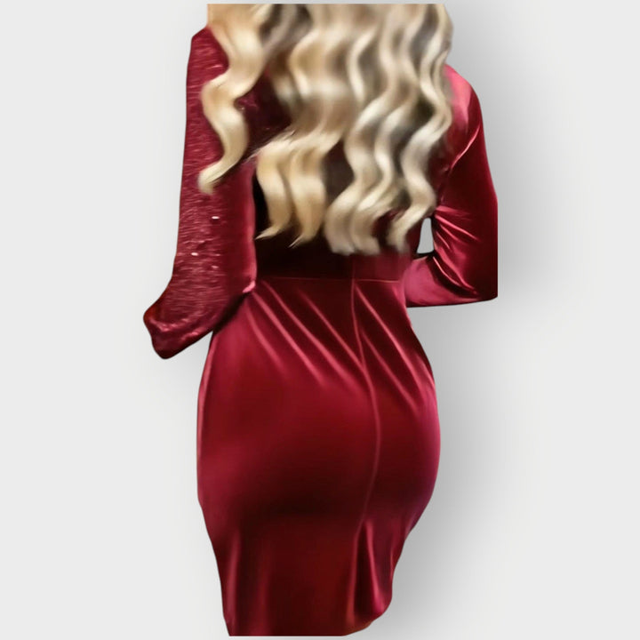 Elegant party dress with flowing fabric worn by a woman on a plain background.