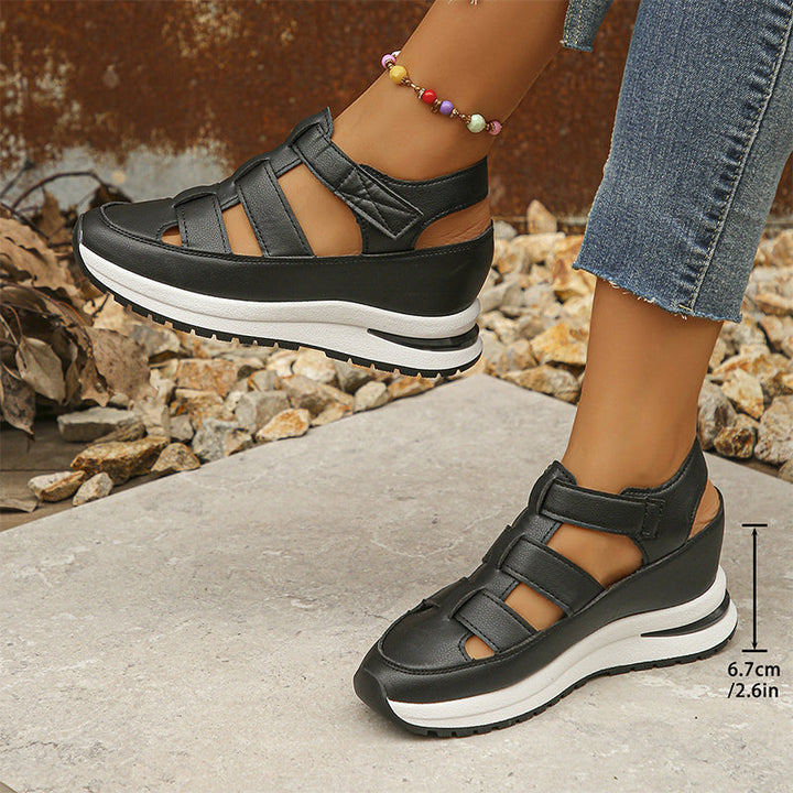 Female feet wearing white elevated sneakers on a plain background.