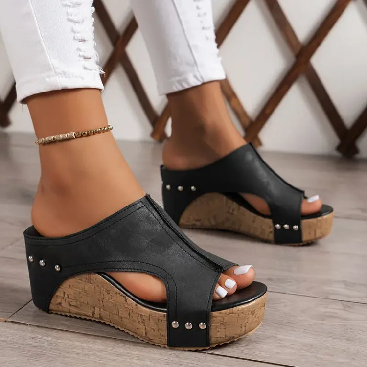 Feet wearing women’s orthopedic cushioned sandals on a plain background.
