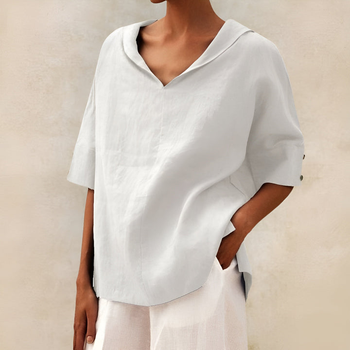 Women’s relaxed blouse displayed on a plain background with soft draped fabric and elegant everyday styling.