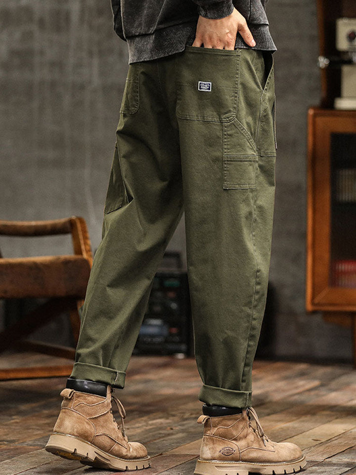 Male model in wide-fit utility pants with a contemporary streetwear look on a plain background.