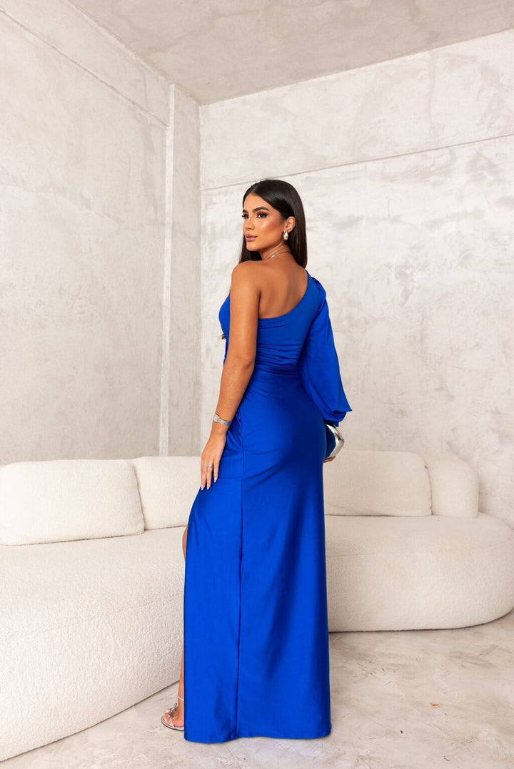 Woman in a feminine long dress with soft movement against a plain background.