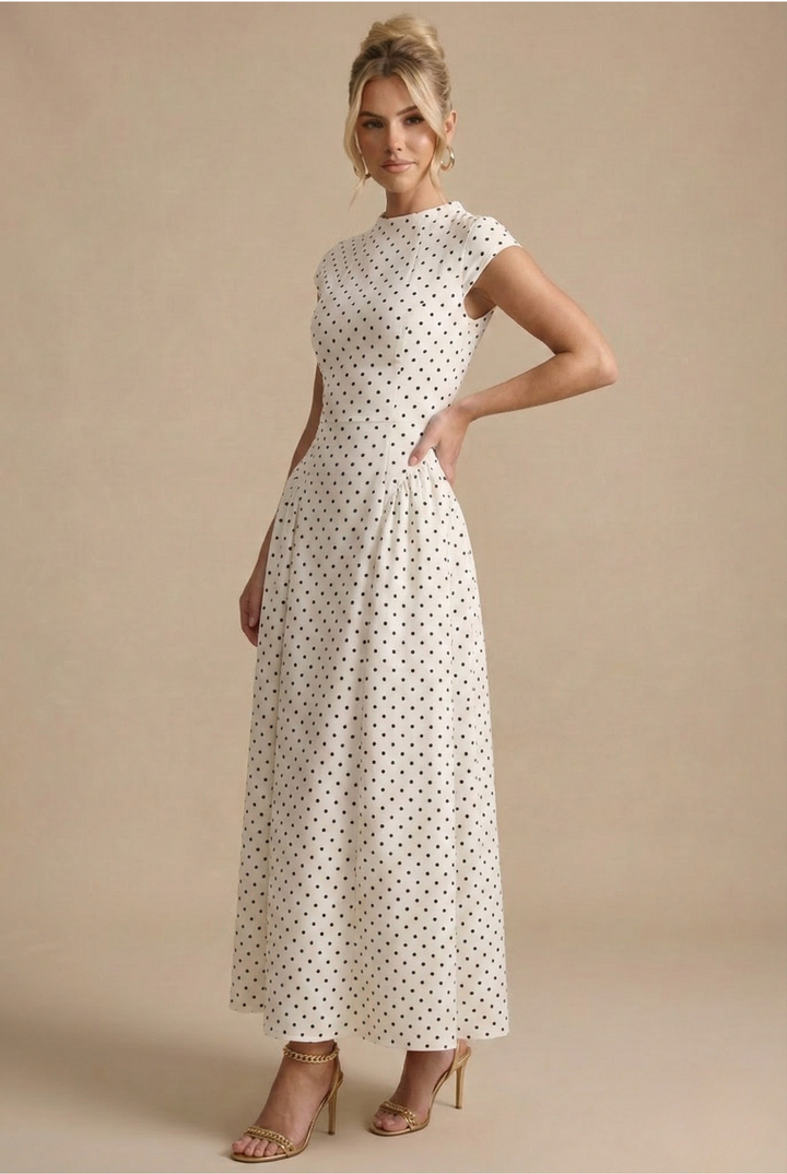  Female model in a sleeveless A-line maxi dress featuring an allover polka dot pattern on a plain background.