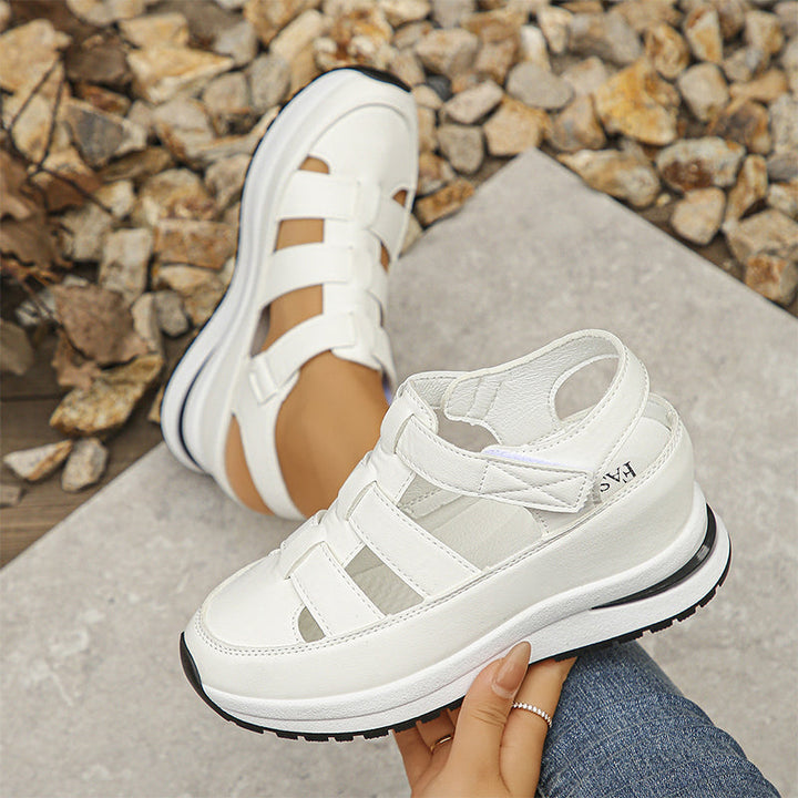 Model showing feet in white everyday sneakers on a plain backdrop.