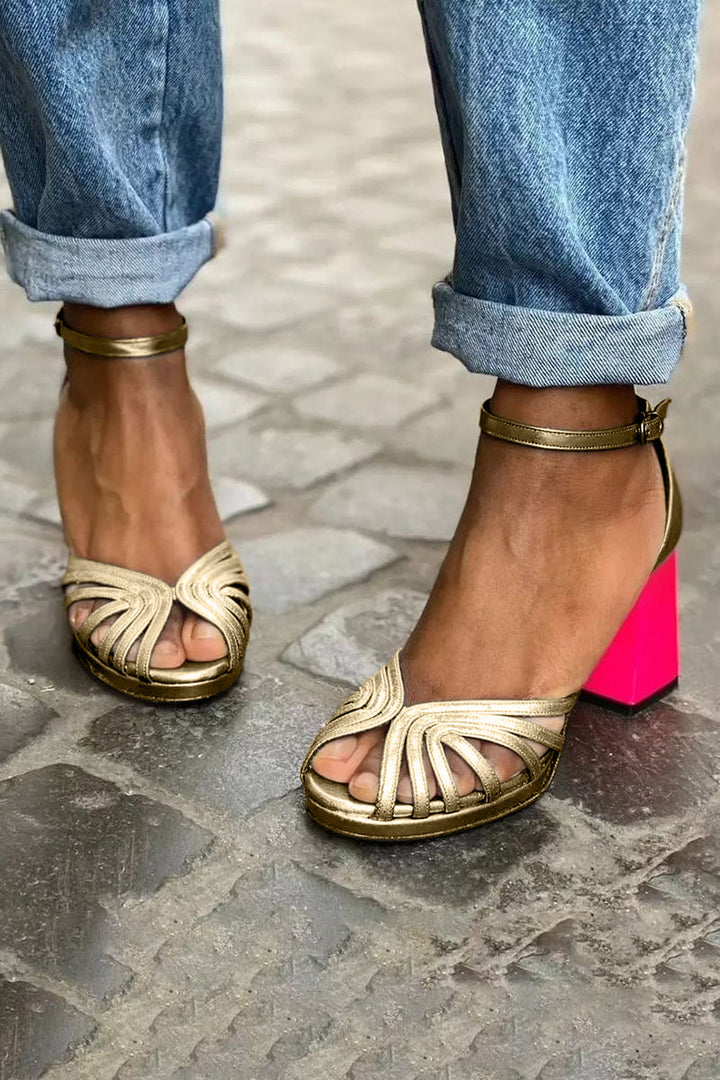 Close-up of a foot in a stylish ankle strap heel on a clean background.
