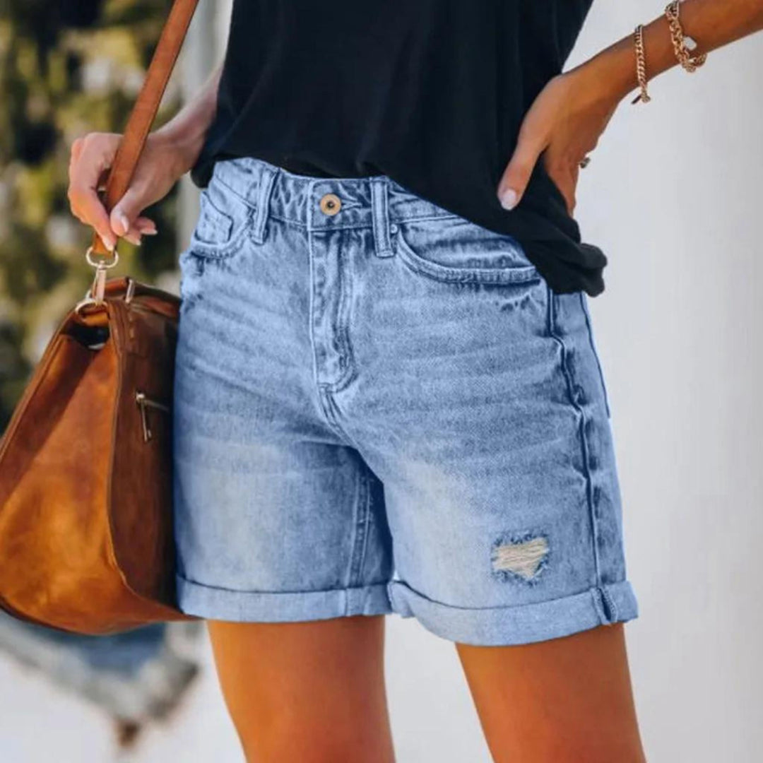 Woman in tailored high waist shorts against a plain background.