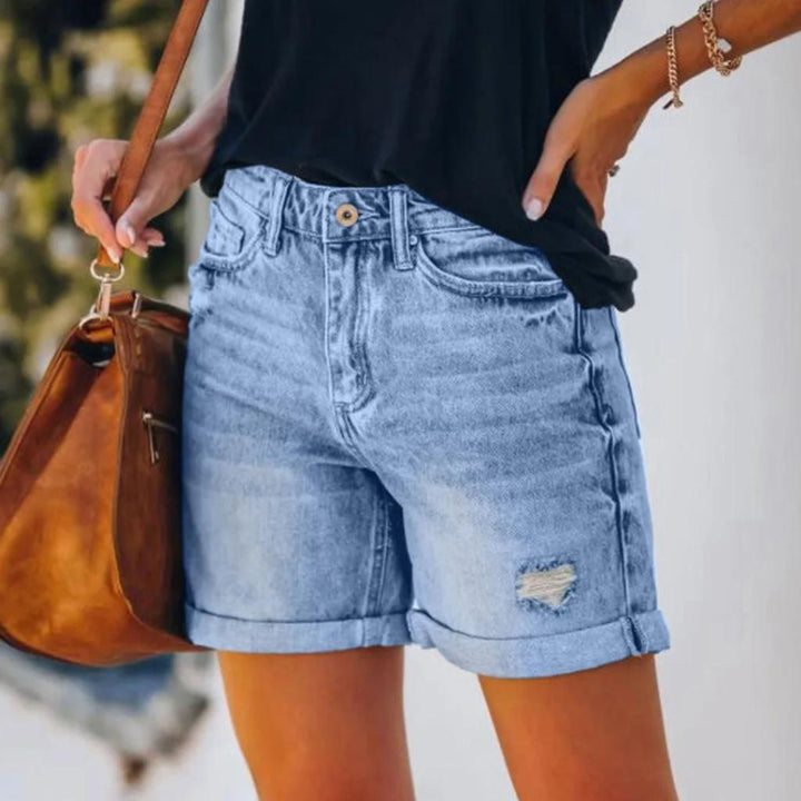 Woman in tailored high waist shorts against a plain background.
