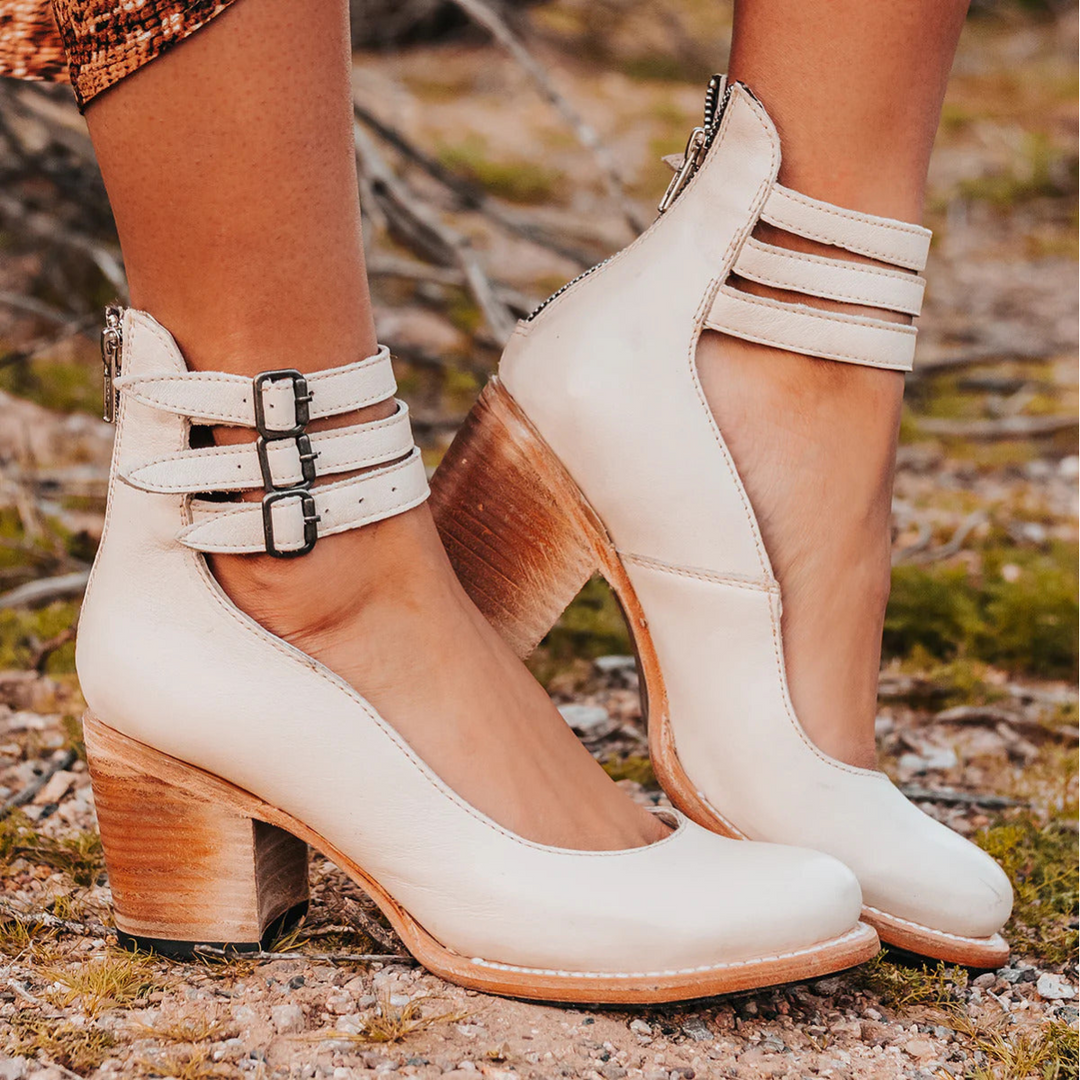 Female foot wearing refined casual sandal with nature background.