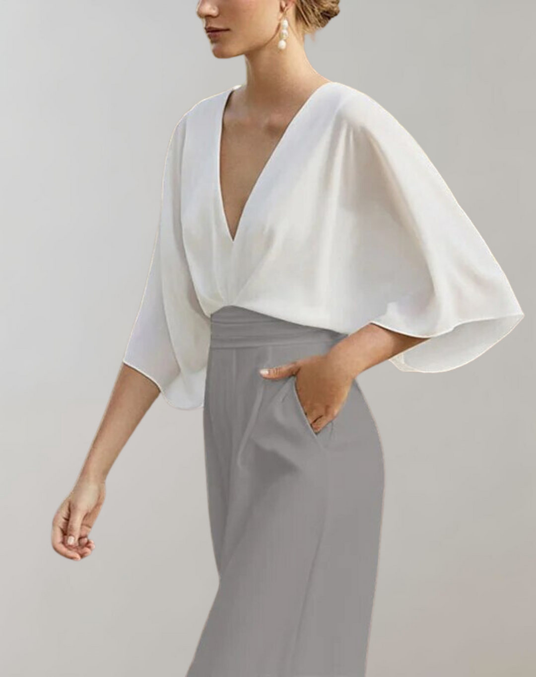 Chic deep neckline jumpsuit styled on a woman against a minimal background.