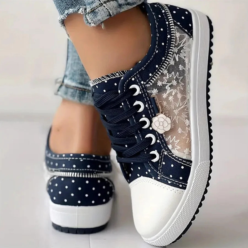 Female feet wearing breathable walking sneakers on a plain backdrop.