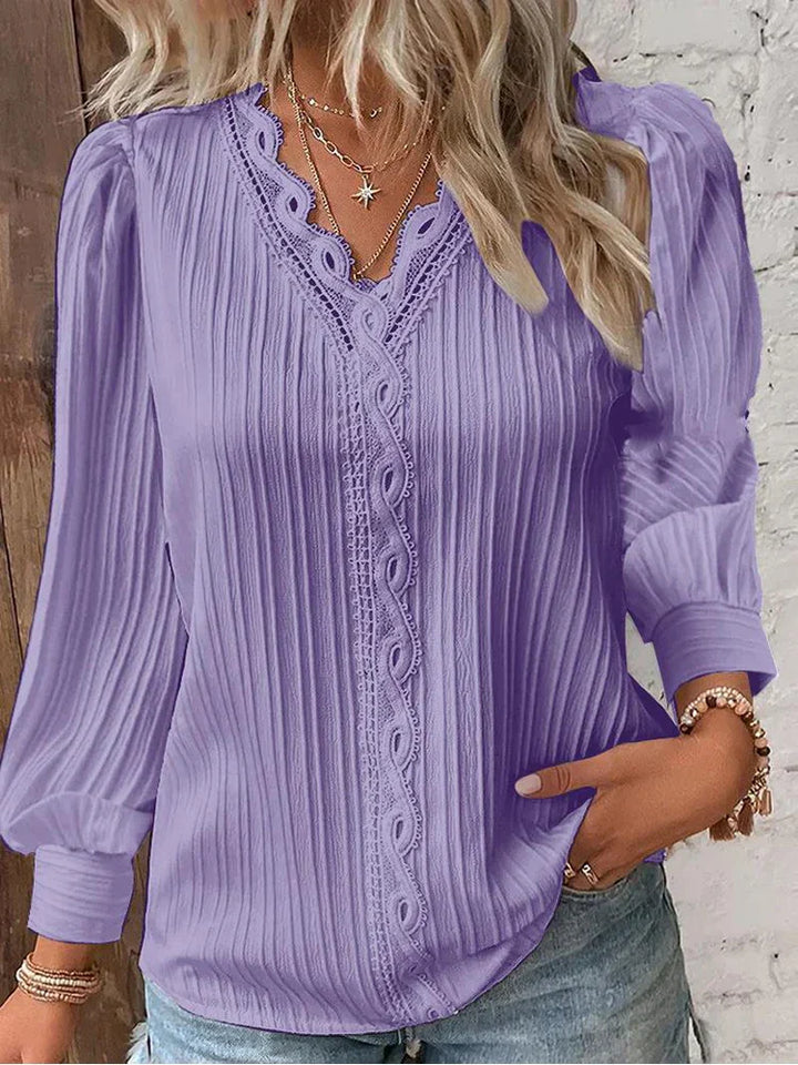 Flowy women’s blouse with lace accents displayed on a clean background.