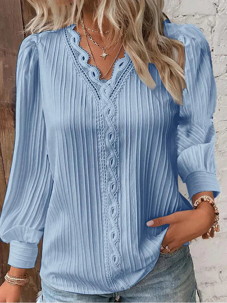 Feminine lace accent blouse styled with a soft flowing silhouette on a plain background.