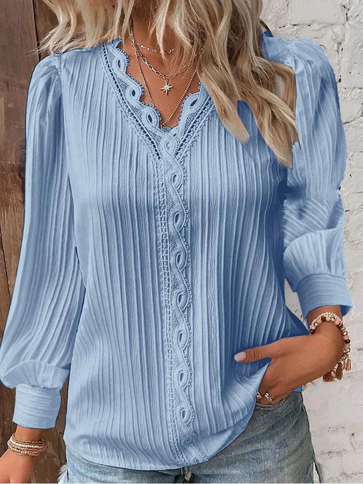 Feminine lace accent blouse styled with a soft flowing silhouette on a plain background.