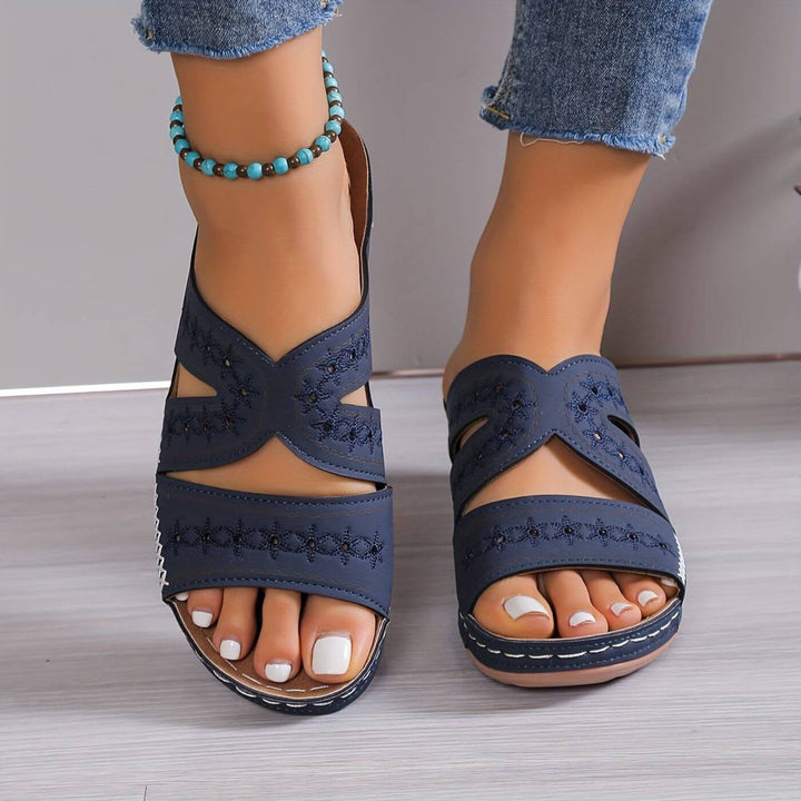 Female model standing in supportive sandals with a clean background.