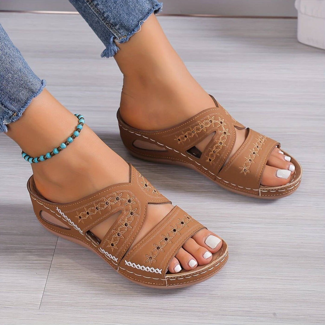 Woman showcasing cushioned footbed sandals on a plain background.