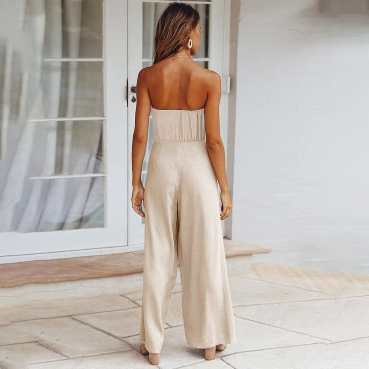 Woman in a bandeau jumpsuit with self-tie waist on a plain background.